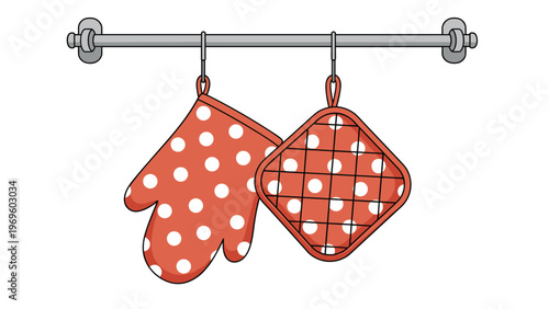 Pair of bright orange kitchen accessories including a polka dot oven mitt and matching potholder hanging from a gray metallic rail.