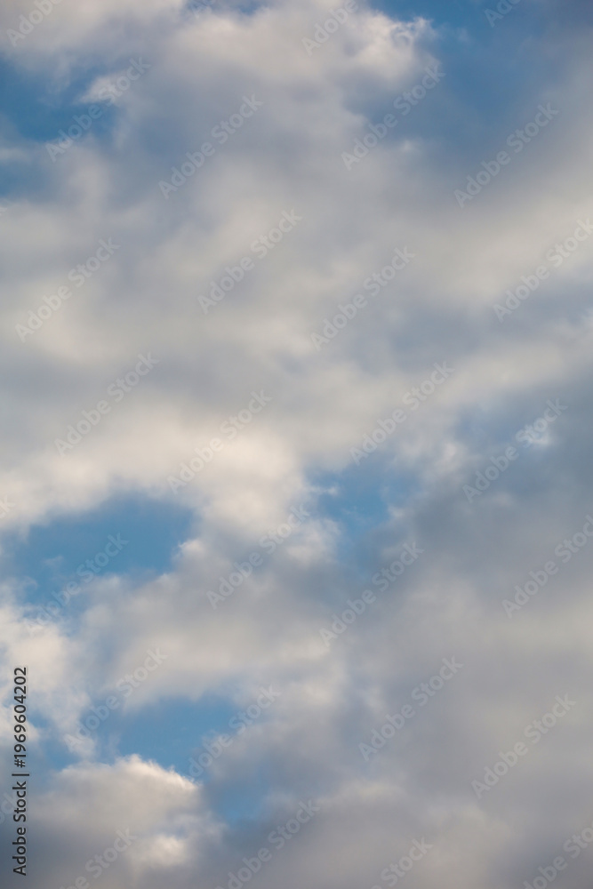 Fototapeta premium Cloudy sky with fluffy white and gray cumulus clouds. Vertical heaven background