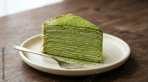 A slice of elegant matcha mille crepe cake showing detailed thin layers and cream, dusted with matcha powder on a ceramic plate, rustic dark wood table, appetizing food photography filling 16:9 frame.