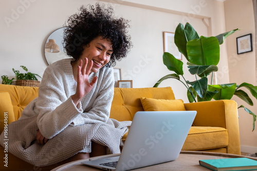 Woman waving during a video call at home