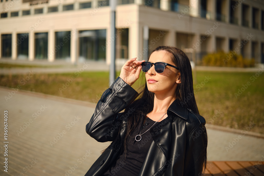 Fototapeta premium Woman in sunglasses enjoying sunny day outdoors near building
