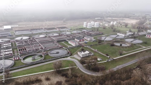 Wastewater Treatment Plant with Multiple Clarifier Tanks in Foggy Landscape