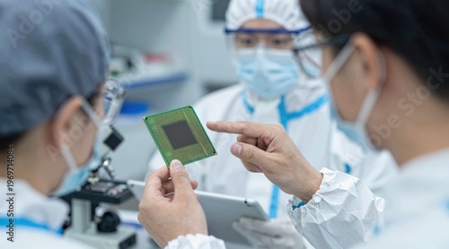 Male and female workers in protective clothing inspecting silicon wafers while looking at a tablet in a semiconductor factory