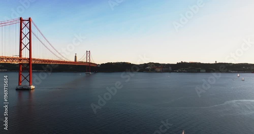 Cinematic sunset over Lisbon Portugal 25th April red suspension bridge famous iconic landmark and Tagus waterfront