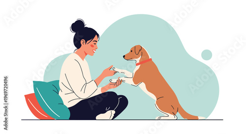 Young woman sitting on the floor smiles while playing with her dog and teaching it a trick to give a paw for friendship.