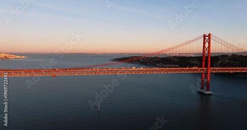 Sunset reflections beneath Lisbon Portugal 25th April red suspension bridge famous iconic landmark over Tagus