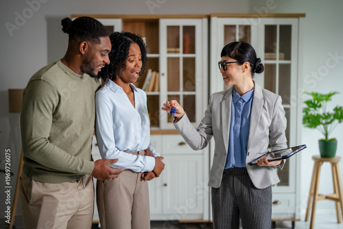 Real estate agent handing over house keys to emotional couple