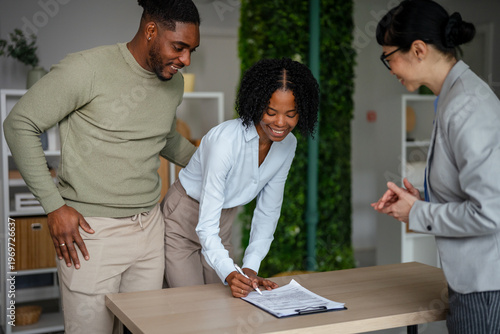Young couple signing agreement with real estate agent