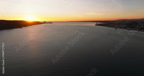 Wide cinematic sunset view of Lisbon Portugal 25th April red suspension bridge famous iconic landmark