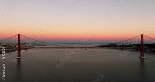 Sunset glow across Lisbon Portugal 25th April red suspension bridge famous iconic landmark over Tagus