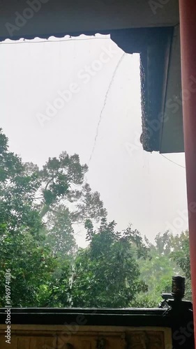 Rainwater Streaming from an Overhanging Roof During a Downpour in a Lush Garden