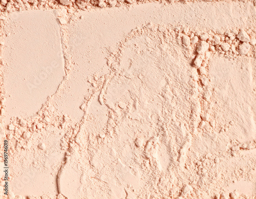 Tactile makeup powder texture with rough pressed surface and scattered cosmetic particles. Neutral beige beauty background ideal for cosmetic branding, packaging design, editorial projects