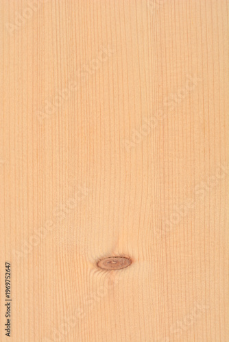 A close up view shows the smooth surface and fine vertical grain of a light brown wooden board with one small dark knot
