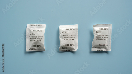 Fotografie White Silica Gel Desiccant Packets on Blue Background for Moisture Protection