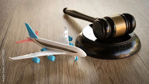 Toy airplane next to a wooden judge gavel on a wooden surface.