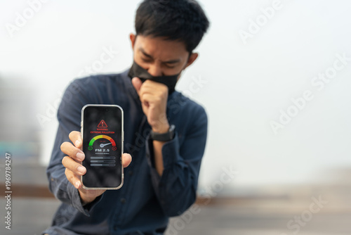 Asian man wearing face mask feeling unwell from air pollution and PM2.5 outdoors.
