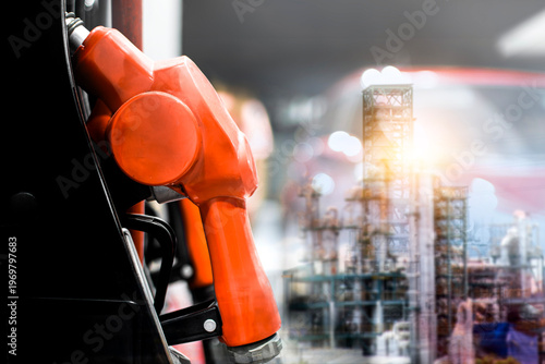 Fuel Nozzle and Refinery Plant, A close-up of a red fuel pump nozzle overlaid with a double exposure of a lit industrial refinery at night for gas and oil themes.