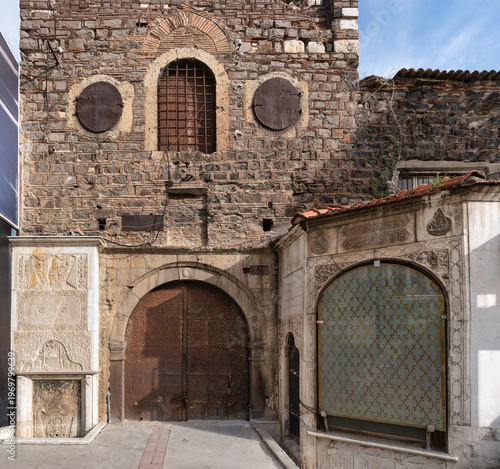 Historic 7 Uyuyanlar Cesmesi, Seven Sleepers Fountain, a weathered stone building with an arched door and ornate marble fountain in Konak, Izmir, Turkey