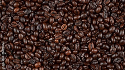 Top-down rotating background of dark roasted coffee beans. Premium glossy flat lay texture for cinematic cafe and barista video projects.