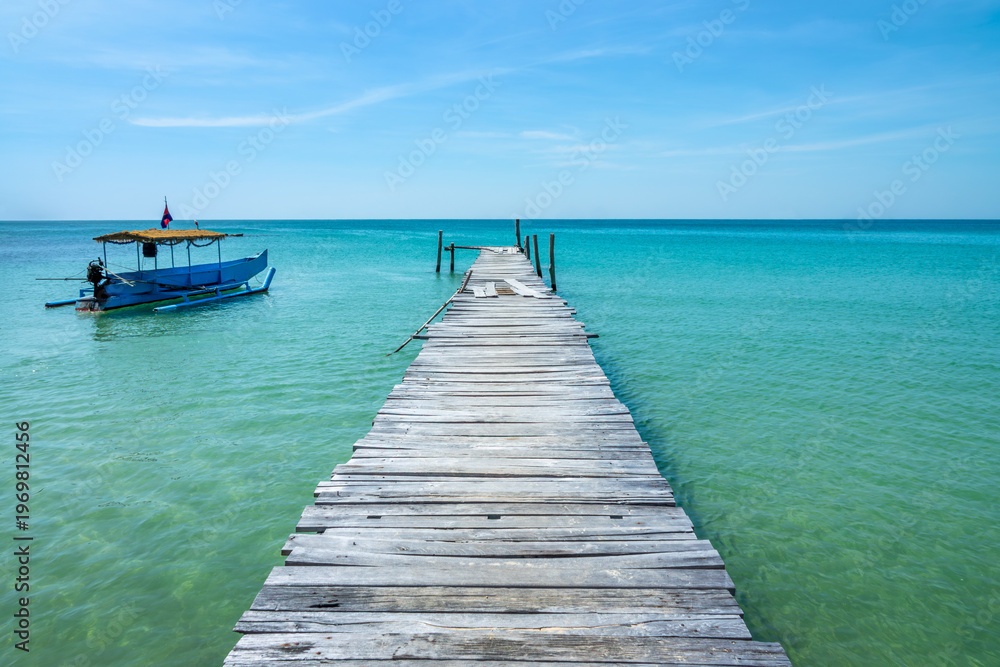 Fototapeta premium Old jetty over turquoise water and traditional cambodian boat on a beach on the island of Koh Rong Sanloem near Sihanoukville, Cambodia