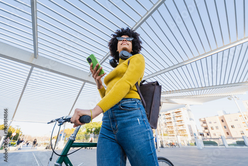 Foto Young woman enjoying urban cycling lifestyle, using smartphone