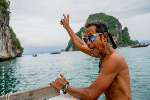 Photography Thai boatman showing peace sign in phang nga bay