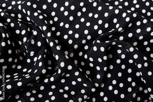 Delicate black fabric with white polka dots. Wavy fashion background for graphic projects, featuring a classic pattern, femininity, lightness, and Italian style.