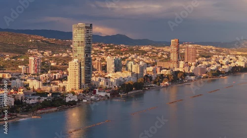 Aerial drone view of Limassol coastline showing modern architecture, residential buildings and calm Mediterranean waters under soft evening light