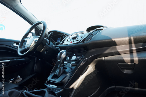 Modern car interior with steering wheel, dashboard, and automatic gear shift. Clean automotive cabin design and transportation concept