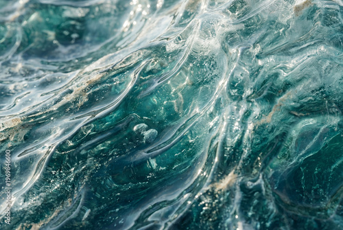 Abstract macro background of turbulent blue sea water featuring flowing liquid ripples, white sea foam, and bright sparkling sunlight.