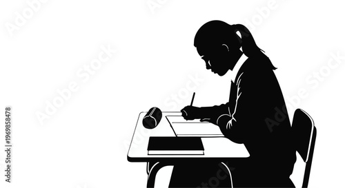 Silhouette of young girl sitting at desk writing with pencil on paper in school or home office setting with cup and books