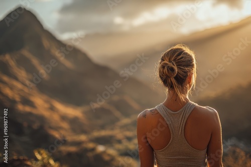 Back-view of a woman meditating at sunrise on a mountain ridge, peaceful nature travel lifestyle scene