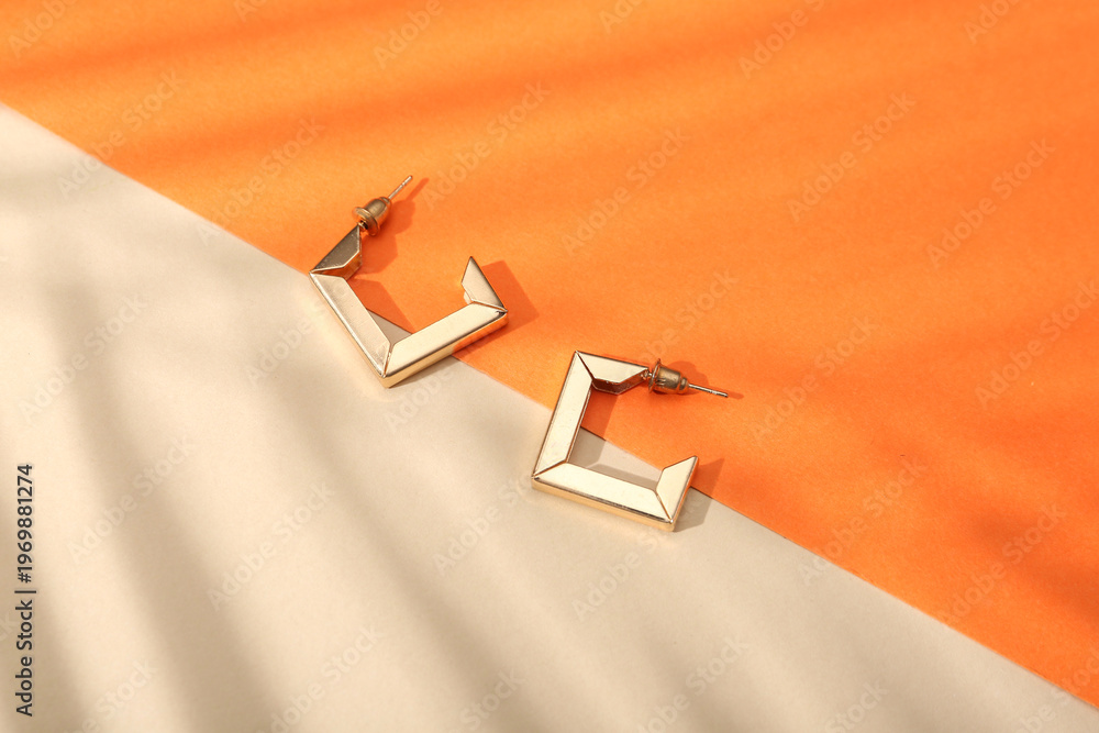 Naklejka premium Beautiful golden earrings on colorful background
