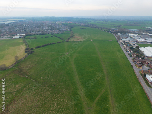 Aerial view of expansive green fields meeting the edge of a built-up area under a muted sky, Southampton, United Kingdom.