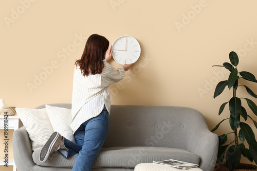 Young woman hanging clock o...