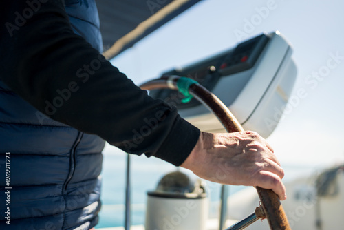 Person steering yacht helm, navigating blue sea