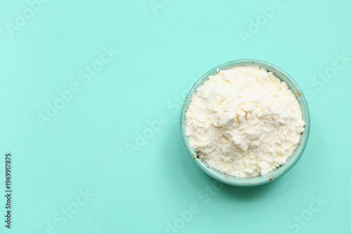 Schilderij op canvas Bowl of powdered milk on turquoise background