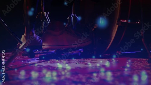 Musician's foot pressing bass drum pedal with floating blue lights maintaining steady music beat