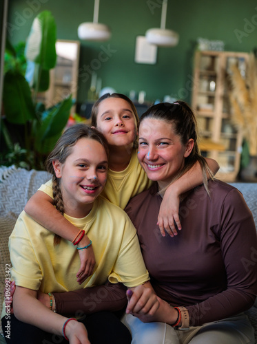 Fotografie Happy family portrait of a mother embracing her two preteen daughters, all smili