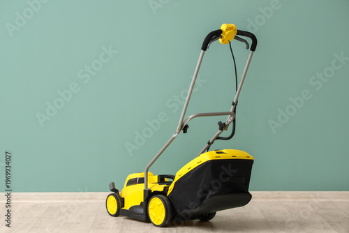 Lawn mower near green wall ...