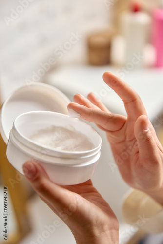 Foto Hand holding cosmetic cream jar with soft texture close up