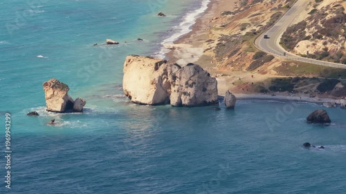 Aerial drone view of Aphrodite's Rock with turquoise sea and nearby coastal road, one of Cyprus' most famous natural landmarks