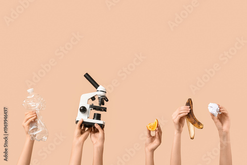 Female hands with modern microscope and different garbage on brown background