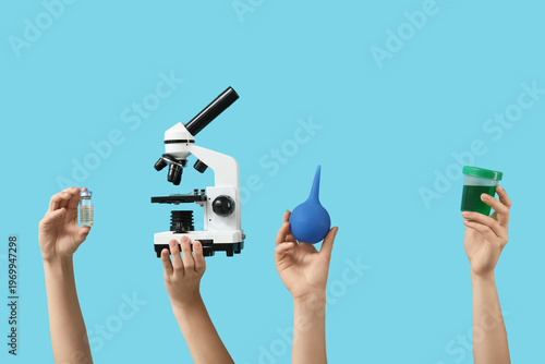 Female hands with modern microscope, ampule, enema and jar of sample on blue ...