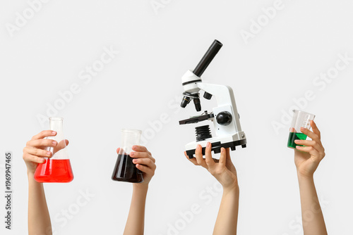 Female hands with modern microscope and laboratory glassware of samples on gr...