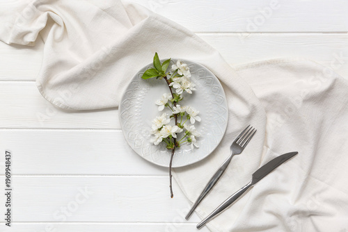 Beautiful table setting with blooming branch on white wooden background