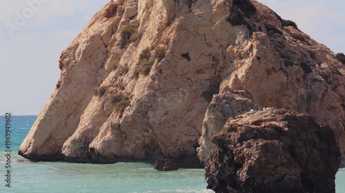 Aerial drone view of a rugged rock formation surrounded by clear blue water along the Cyprus coastline