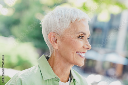 Photos Confident senior woman outdoors in a city setting smiling in a casual green shir