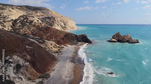 Aerial drone view of rugged cliffs and rocky beach with waves washing onto the shore in Cyprus