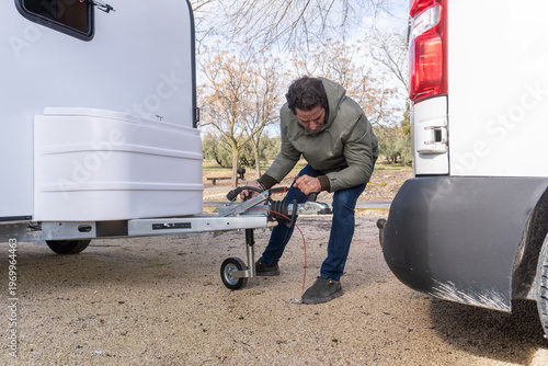 Canvas Print Man preparing to tow a trailer or caravan, adjusting the hitch connection to a m